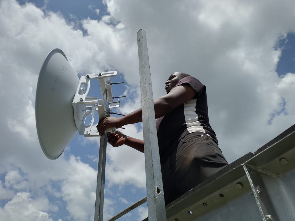 Fred Installing Network Dish on top of a water tank.